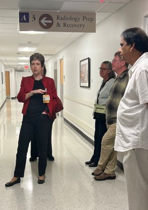 Doctor Ann Fulcher wearing red jacket standing and speaking to three men and one woman in a hospital corridor