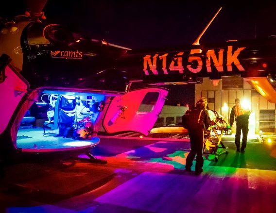 Two Helicopter EMT staff rolling critically injured patient into E R