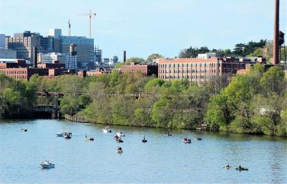 A sunny day with boats on James River and railroad tracks in front of VCU Health and Shockoe Bottom apartments