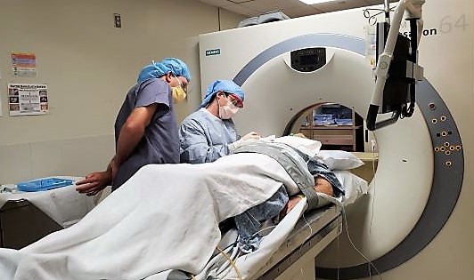A radiology resident with an attending physician conducting a CT guided biopsy