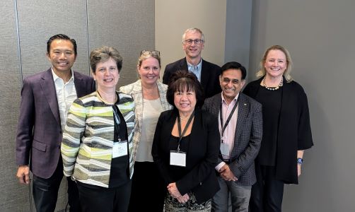 Seven people standing together wearing business suites