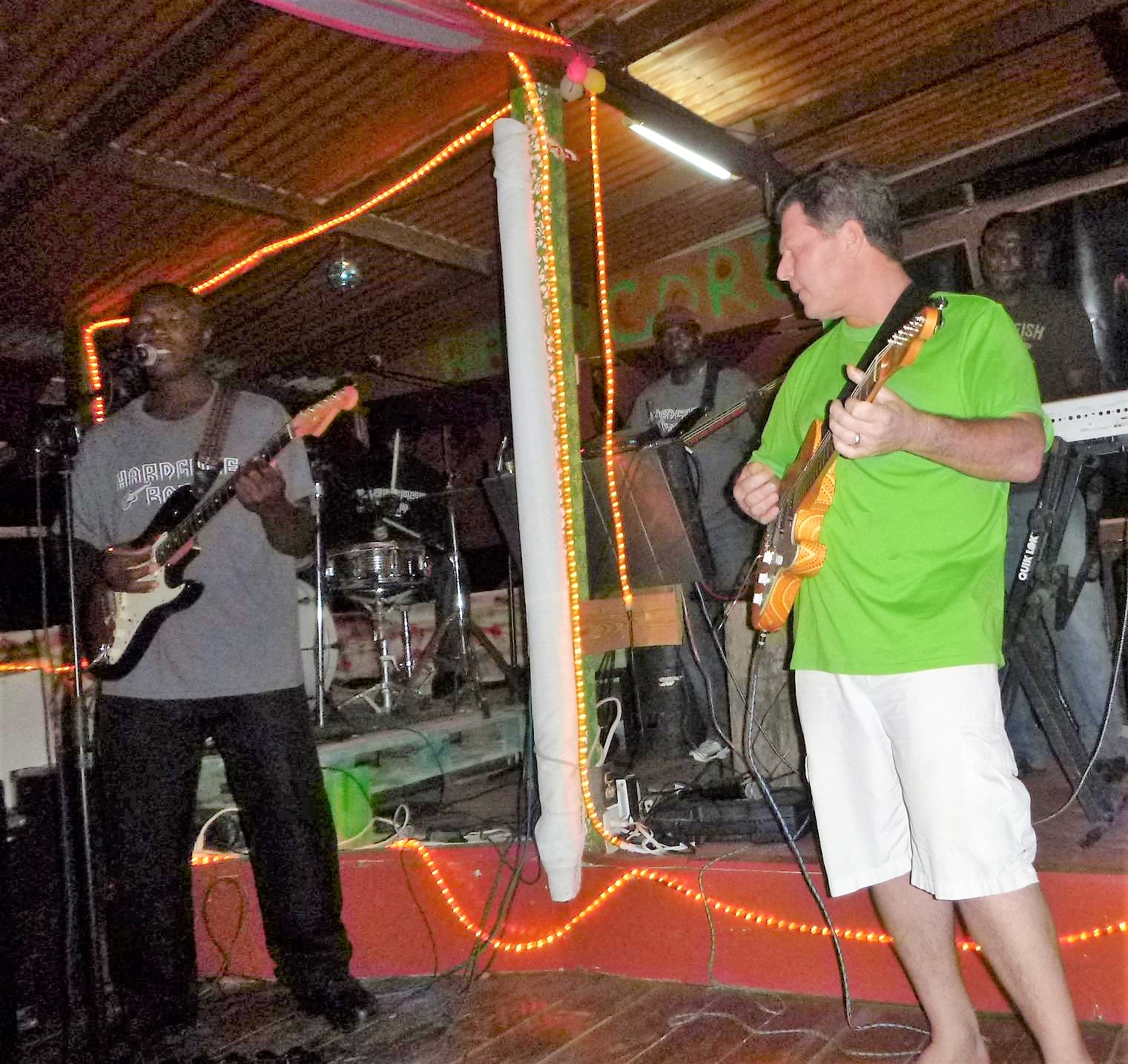 Mike Aronson playing guitar on stage with a Reggae band in Antigua