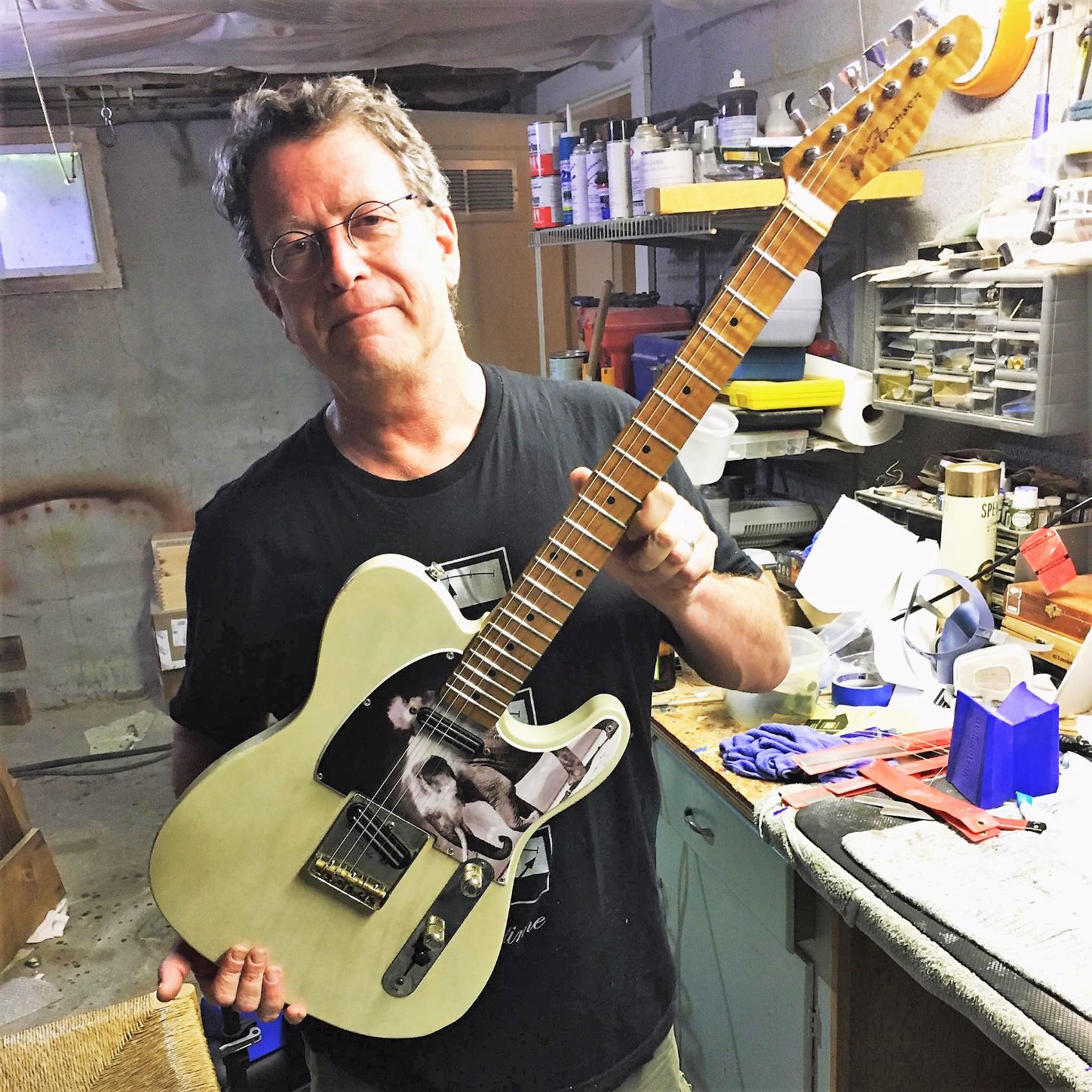 Radiologist Mike Aronson holding a custom electric guitar in his workshop