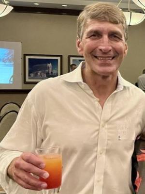 Doctor Robert Bulas in a white button up shirt holding a glass with an orange drink