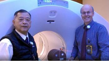 Two male diagnostic medical physicians standing next to medical scanner
